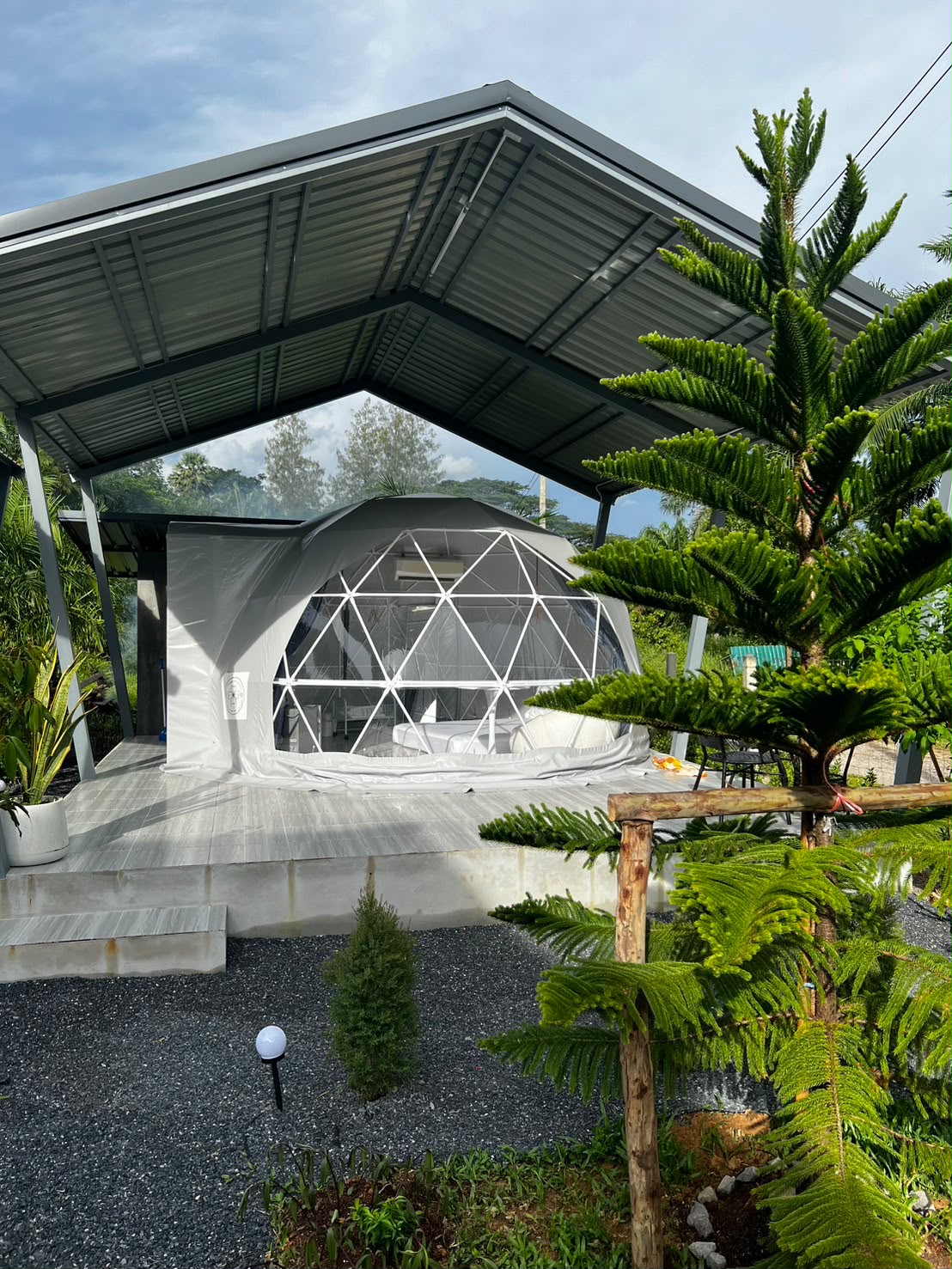 A dome stay at Wanasa in bright sunshine, surrounded by garden planting